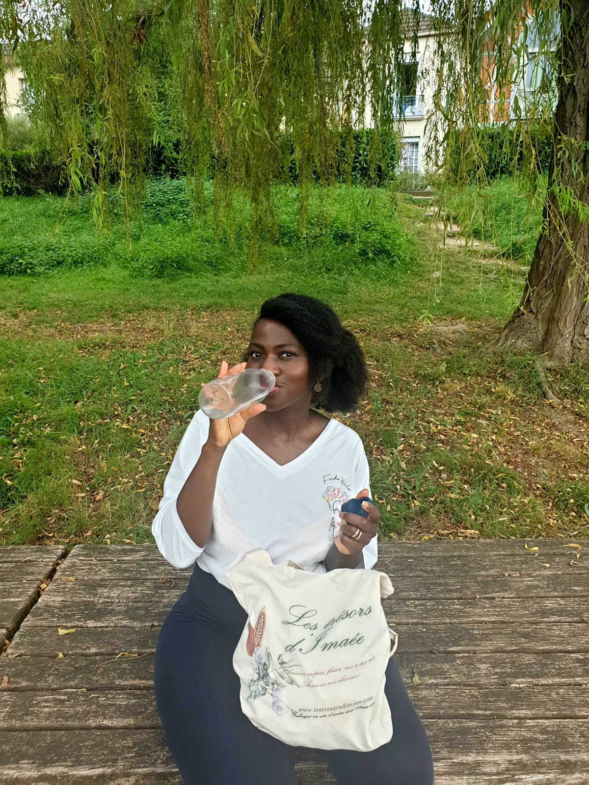 Une fille avec de beaux cheveux crépus est en qui utilise les soins capillaires Les Trésors d'imaée est train de s'hydrater